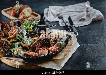 Verschiedene Meeresfrüchte, Garnelen, Jakobsmuscheln, Tintenfisch, Muscheln. Servierteller auf dem Tisch mit einer Reihe von Meeresfrüchten. Klassische italienische Küche. Stockfoto