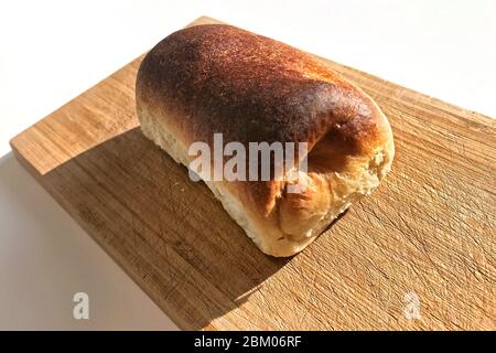 Frisch gebackenes Brötchen mit Hüttenkäse Füllung steht auf dem Schneidebrötchen. Stockfoto