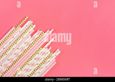 Trinkpapier Strohhalme für Party mit goldenen, weißen, rosa Streifen auf rosa Pastell Hintergrund mit Kopierraum. Draufsicht der bunten Papier Einweg Öko Stockfoto