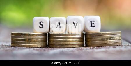 Geld sparen, Sparkonzept - Würfel auf Goldmünzen, Nahaufnahme Stockfoto