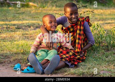 Zwei Masai-Kinder sitzen zusammen auf Gras Stockfoto