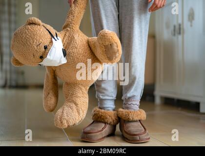 Teenager-Mädchen Umarmung Teddybär mit Gesichtsmaske. Konzept des Corona-Virus, zu Hause bleiben, Isolation. Verhinderung von Grippeviren Stockfoto