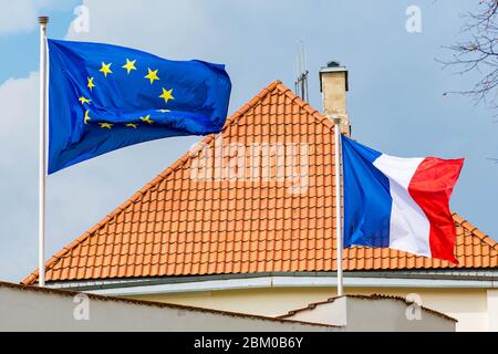 Europäische Union und französische Flagge winken zusammen mit Dach eines Hauses auf Hintergrund Stockfoto
