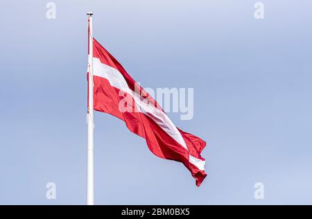 Lettische Nationalflagge auf Fahnenmast, Flagge Lettlands winkt in Riga Stockfoto