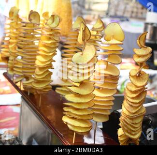 Gebratene Kartoffelspirale auf einem Stock während des Street Food Festivals. Fast Food. Tornado Kartoffeln auf einem Bambusstock Stockfoto