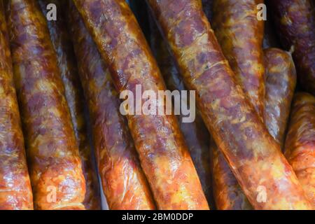 Würstchen hängen draußen während des Straßenessen-Festivals. Produktionslinie für Wurst. Wurst auf der Theke für die Räucherei. Industriefertigung Stockfoto