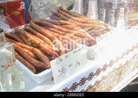 Würstchen hängen draußen während des Straßenessen-Festivals. Produktionslinie für Wurst. Wurst auf der Theke für die Räucherei. Industriefertigung Stockfoto