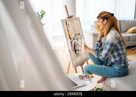 Schöne Frau Malerei auf Leinwand in ihrem Haus oder Werkstatt Stockfoto