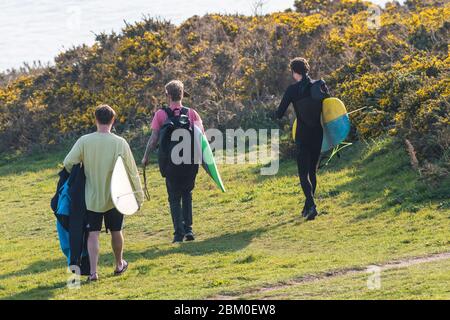 Surfer tragen ihre Surfbretter und laufen zum Crantock Beach in Newquay in Cornwall. Stockfoto