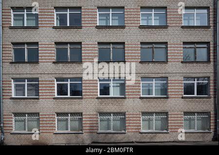Fassade der sowjetischen Platte grau mit orange alten Gebäude mit Fenstern. Typische Schule, Krankenhaus Gebäude in der UdSSR. Stockfoto