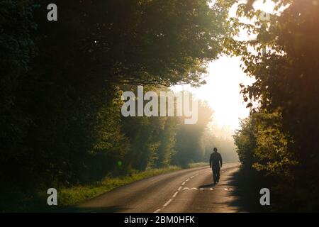 Ein Mann geht an einem nebligen Morgen im Fairburn ings Nature Reserve entlang einer Landstraße. Stockfoto