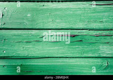 Nahaufnahme der abblätternden Farbe gegen grün verblichene verrotternde Holzpaneele Stockfoto