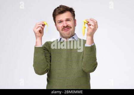 Lustige kaukasische Mann mit popped gelben Ballon auf weißen Wand isoliert. Studioaufnahme Stockfoto