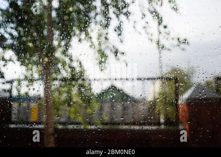 Regentropfen auf der Fensterscheibe. Verschwommener Hintergrund vor dem Fenster im Regen. Stockfoto