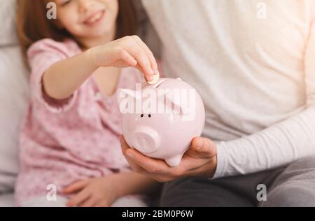 Cropped von Mädchen, das Geld in Sparschwein Stockfoto