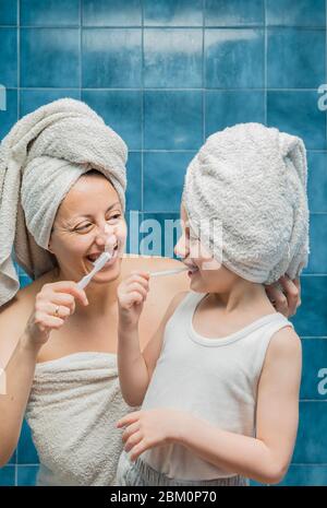 Eine Frau und ein Junge mit Handtüchern auf dem Kopf putzen ihre Zähne. Stockfoto