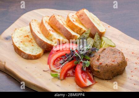 Steak mit Tomaten, Gurken und in Scheiben geschnittenem Brot auf einem Holzbrett Stockfoto