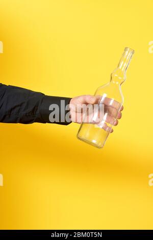 Mann mit einer transparenten Flasche auf gelbem Hintergrund Stockfoto