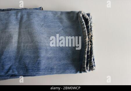 Nahaufnahme und selektive Konzentration auf ausgefranste Beine einer Jeans auf rauem weißen Tisch platziert Stockfoto