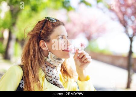 Junge Rotschopf Frau riecht Kirschblüte im Park während Sakura, Blick nach oben Stockfoto