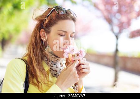 Junge Rotschopf Frau riecht Kirschblüte im Park während Sakura Stockfoto