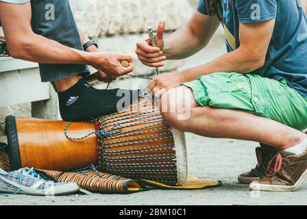 Moskau, Russland - 1. JUNI 2014: Zwei junge Männer richten das ehnische Percussion-Musikinstrument jembe ein und bereiten es vor Stockfoto