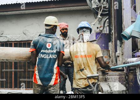 Kumasi,Ghana - 20. April 2020: Menschen, die Bohrlöcher mit Bohrmaschine machen und sich auch müde fühlen Stockfoto