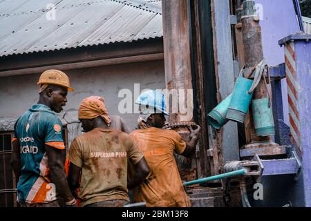 Kumasi,Ghana - 20. April 2020: Menschen, die Bohrlöcher mit Bohrmaschine machen und sich auch müde fühlen Stockfoto