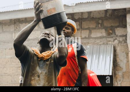 Kumasi,Ghana - 20. April 2020: Menschen, die Bohrlöcher mit Bohrmaschine machen und sich auch müde fühlen Stockfoto