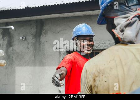 Kumasi,Ghana - 20. April 2020: Menschen, die Bohrlöcher mit Bohrmaschine machen und sich auch müde fühlen Stockfoto