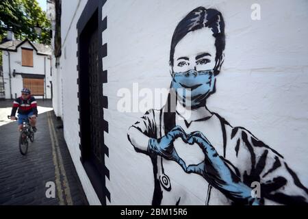Eine Person radelt an einem Kunstwerk des Künstlers vorbei, der als Rebellbär bekannt ist, nachdem es an einer Wand in der Ashton Lane in Glasgow erschien. Die neue Ergänzung zu Glasgows Street Art fängt die globale Coronavirus-Krise ein. Das Stück zeigt eine Krankenschwester, die eine Maske trägt und mit ihren Händen ein Liebesherz bildet, während Großbritannien weiterhin im Lockdown bleibt, um die Ausbreitung des Coronavirus zu verhindern. Stockfoto