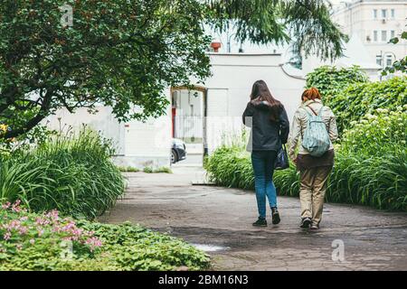 Moskau, Russland - 7. JULI 2017: Zwei junge Frauen gehen durch die Straßen der Stadt. Sie gehen in Richtung Parktor. Rückansicht Stockfoto