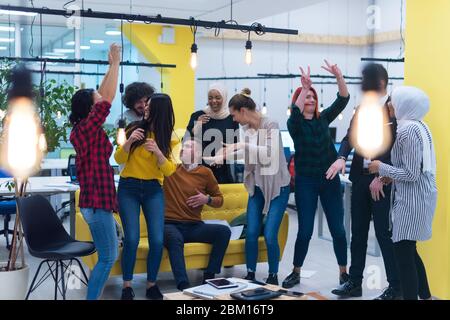 Young Business Team feiert einen guten Job im Büro. Gruppe junger Mitarbeiter tanzen im CO-Arbeitsbereich nach erfolgreicher Arbeit. Stockfoto