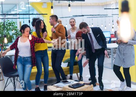 Young Business Team feiert einen guten Job im Büro. Gruppe junger Mitarbeiter tanzen im CO-Arbeitsbereich nach erfolgreicher Arbeit. Stockfoto