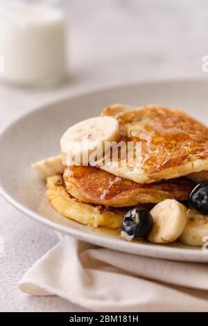 Stapel Buttermilch Pfannkuchen mit Bananen, Sirup und Heidelbeeren gekrönt. Stockfoto