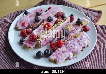 Hausgemachte rosa gefrorene Joghurtbars mit Himbeeren und Heidelbeeren. Snack für die Sommertage Stockfoto