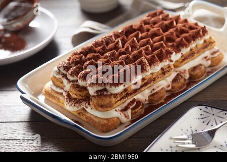 Ganz frisch zubereitetes italienisches Tiramisu-Dessert auf einer großen Platte, serviert am Tisch in einem Nahaufnahme für regionale Küche Stockfoto