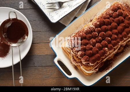 Blick von oben auf ein frisch zubereitetes Tiramisu-Dessert mit Zutaten, die am Tisch für köstliche italienische Küche serviert werden Stockfoto