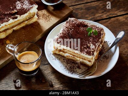 Große Portion frisches italienisches Tiramisu Dessert auf einem Teller am Tisch serviert mit Espresso Kaffee neben in einem hohen Winkel Blick geeignet für ein Menü Stockfoto