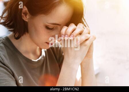 Süßes, wunderschönes Mädchen hat ihre Hände im Gebet gefaltet. Eine Frau bittet Gott um Hilfe. Stockfoto