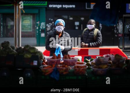 Käufer tragen Schutzmaske an einem Obst- und Gemüsemarkt in East Ham, East London, während Großbritannien weiterhin in der Lockdown-Richtung bleibt, um die Ausbreitung des Coronavirus einzudämmen. Stockfoto