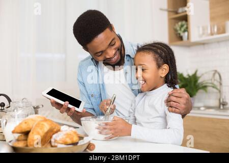 Vater und Tochter machen Gebäck, mit Rezept von digitalen Tablet Stockfoto