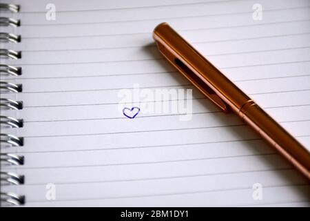 Gezeichnetes Herz in Notizbuch mit Stift. Valentinstag und Liebeskonzept. Stockfoto