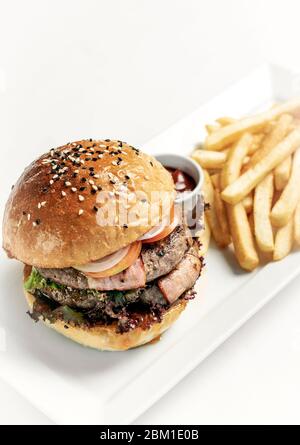 australischer Bio-Rinderburger mit pommes frites-Platte auf weißem Studiohintergrund Stockfoto