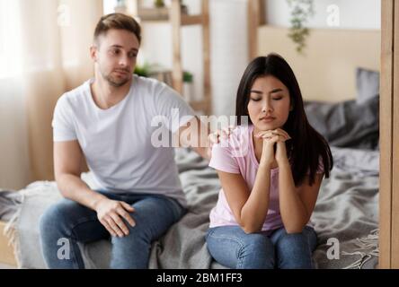 Ehemann berühren beleidigt Frau Schulter sitzen auf Bett zu Hause Stockfoto
