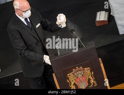 Hamburg, Deutschland. Mai 2020. Ein Mitarbeiter des Landtags Hamburg sprüht das Mikrofon mit Desinfektionsmittel an die Rednerpulte. Quelle: Axel Heimken/dpa/Alamy Live News Stockfoto