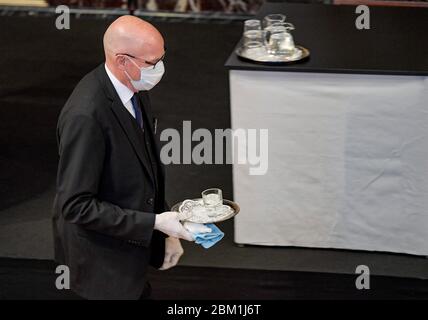 Hamburg, Deutschland. Mai 2020. Ein Beamter des Hamburger parlaments serviert am Rednerpult ein Glas Wasser mit einer Gesichtsmaske. Quelle: Axel Heimken/dpa/Alamy Live News Stockfoto