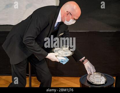 Hamburg, Deutschland. Mai 2020. Ein Mitarbeiter des Hamburger landtags serviert mit einer Gesichtsmaske ein Glas Wasser am Rednerpult. Quelle: Axel Heimken/dpa/Alamy Live News Stockfoto