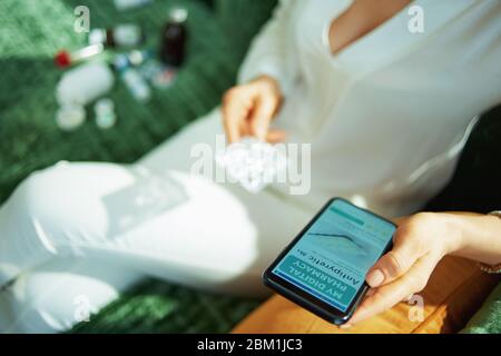 Nahaufnahme auf weiblich mit leeren Blister Packung von Pillen Kauf Apotheke online mit Smartphone im Haus an sonnigen Tag. Stockfoto