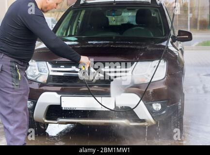 Ein Mann wäscht ein Auto bei einer berührungslosen Autowäsche, ein Mann wäscht ein braunes Auto, Kaliningrad, Russland, 1. März 2020 Stockfoto